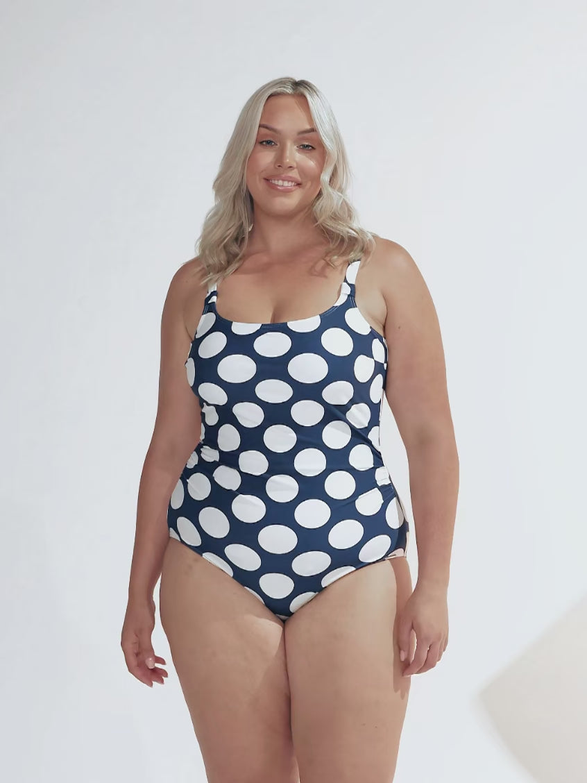 model wearing navy and white large polka dot patterned women's swimsuit