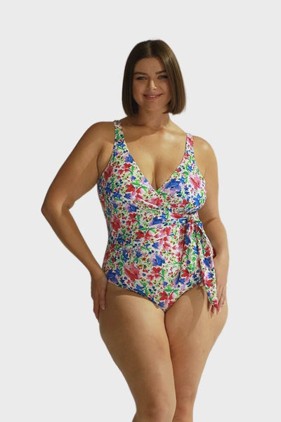 Brunette model wearing colourful crossover tie one piece with scoop back in floral