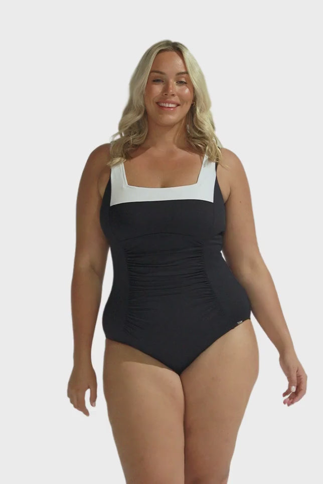 Blonde model wearing black swimsuit with white neck line