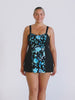 Blonde model in studio wearing a blue and black floral swim dress in chlorine resistant