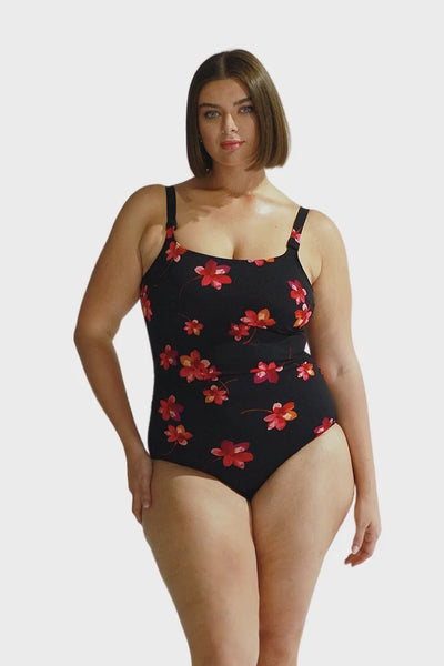 Brunette curve model wearing chlorine resistant tank one piece in black with pink floral print