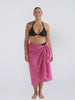 Blonde model wearing a plum colour sarong with pom poms in studio