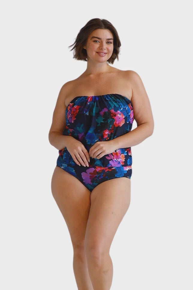 Brunette model wears navy floral flouncy bandeau one piece