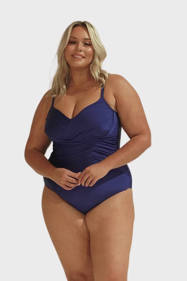 Video of curve model in studio wearing metallic navy one piece with criss cross ruching detail over the bust