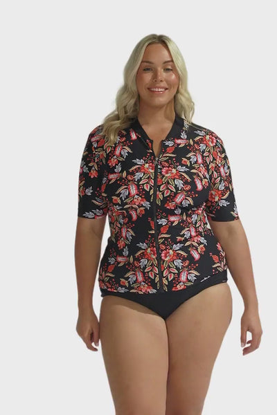 Video of blonde model in studio showing off pink floral printed rash shirt  with black base and zip front detail