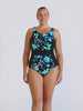 Blonde model in studio wearing a sleeveless zip front one piece in blue and black floral