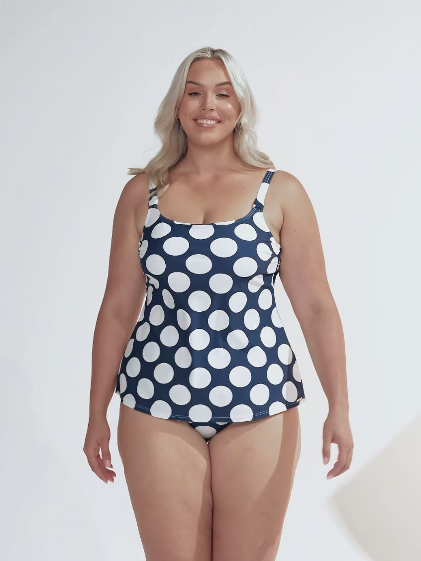 model wearing navy and white large polka dot patterned tankini and matching swim bottom