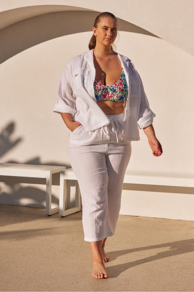 blonde model wearing a white crepe button through set over a bikini with the sleeves rolled up