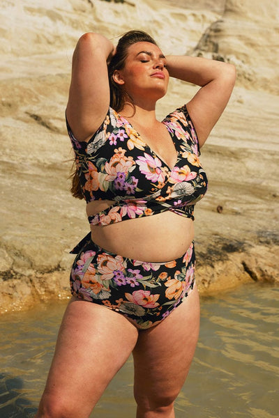 Brunette model wearing black and pink floral wrap swim top