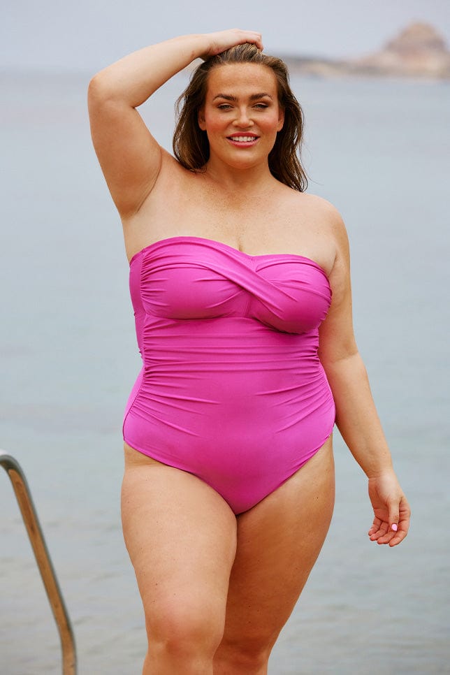 Brunette model wears hot pink strapless one piece