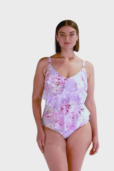 Brunette modelling a three tiered ruffle swimsuit in floral print with tones of purple