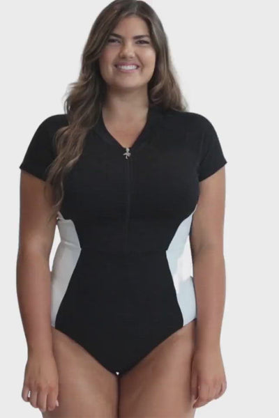video of model wearing a black high necked zip up one piece with cap sleeves and white side panelled detail