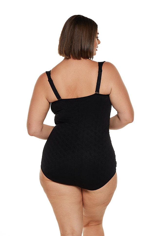 Brunette model wears plus size boyleg skirted one piece with adjustable straps