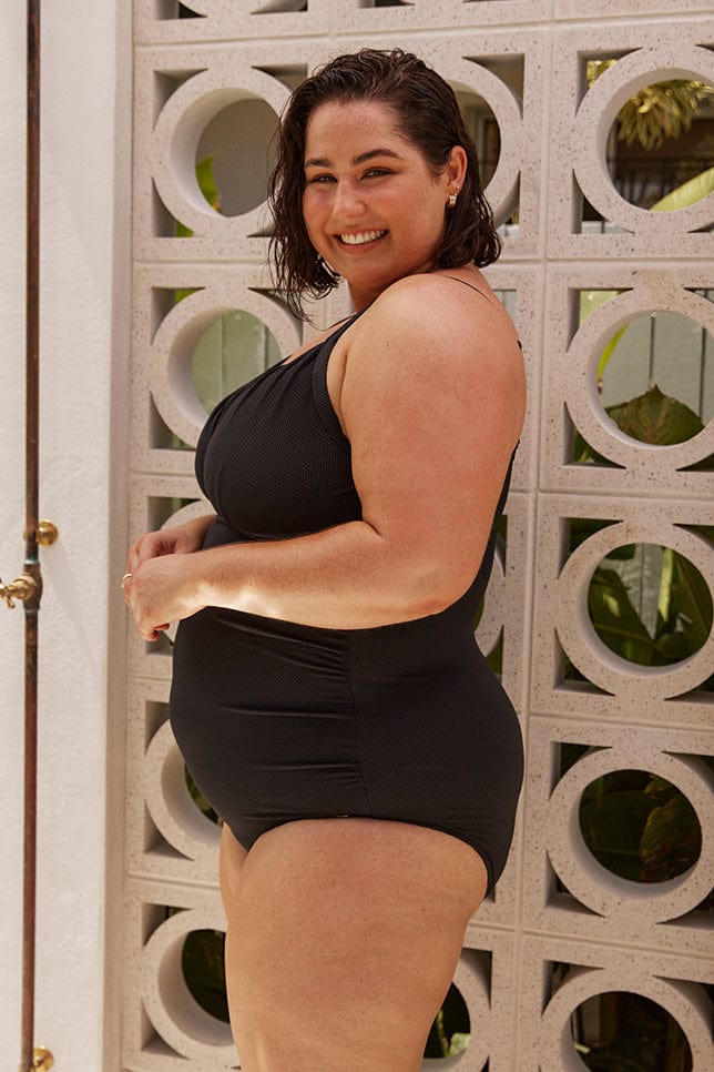Plus size model wears flattering black underwire one piece in textured fabric