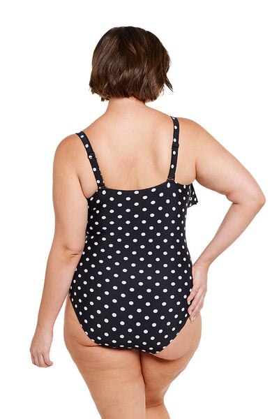 brunette model wears supportive black and white dots one piece with adjustable straps