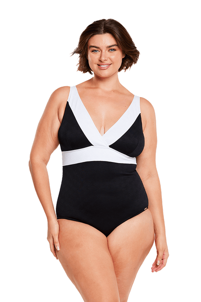 Brunette model wears low neckline white and black one piece swimsuit