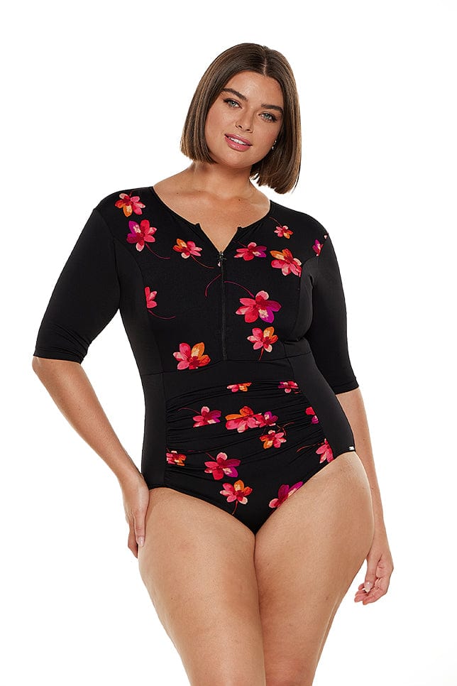 Brunette model wears chlorine resistant black and pink floral one piece with elbow length sleeves