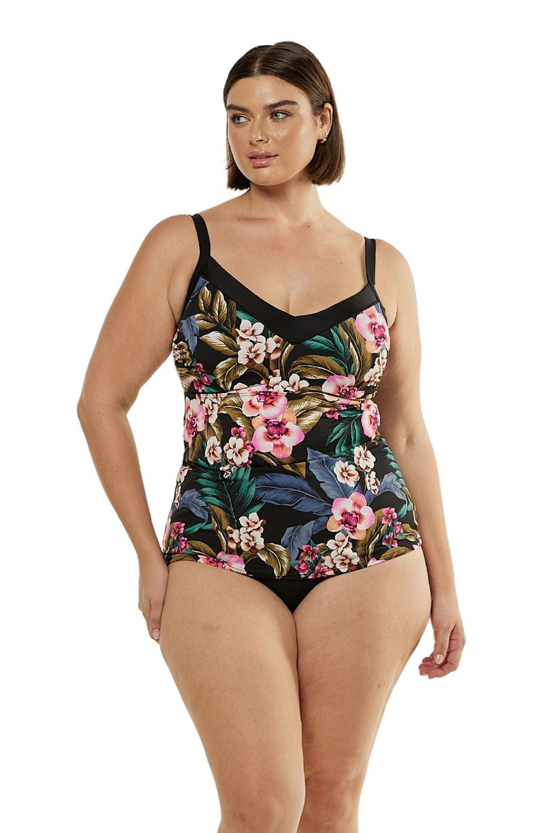 Brunette model with hand on hip wearing curve underwire tankini top with black floral print