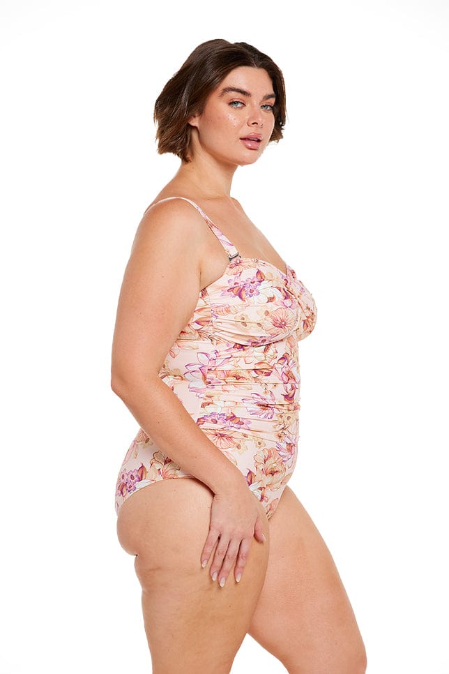 Brunette plus size model wears pink floral bandeau one piece with removable straps