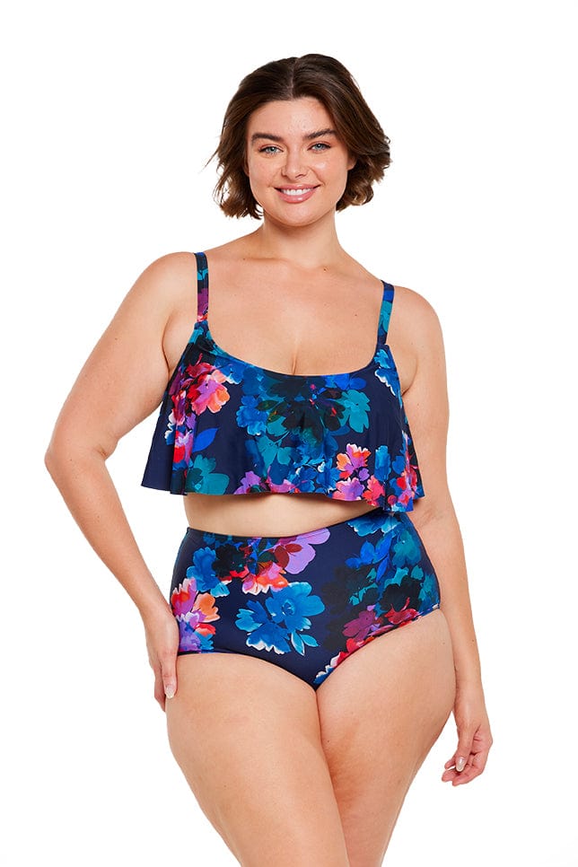 In studio image of a brunette curve model wearing frill bikini top in navy and purple floral print Australia