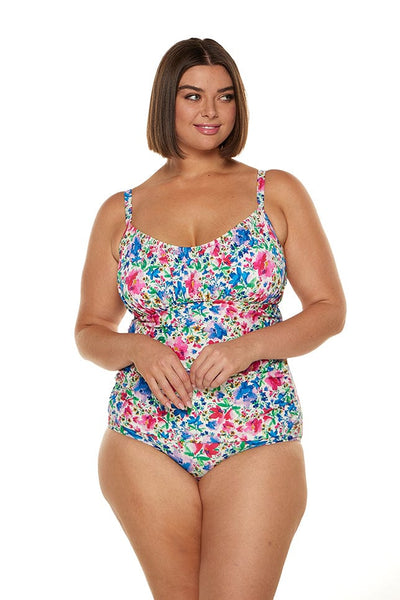 In studio image of brunette plus size model wearing ruched underwire tankini swim top in bright colours