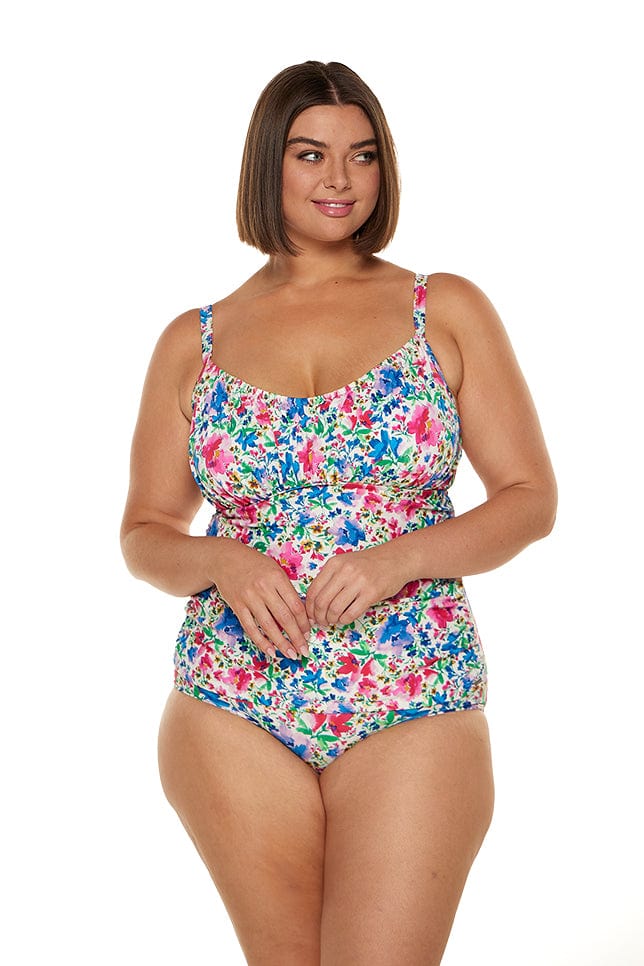 In studio image of brunette plus size model wearing ruched underwire tankini swim top in bright colours