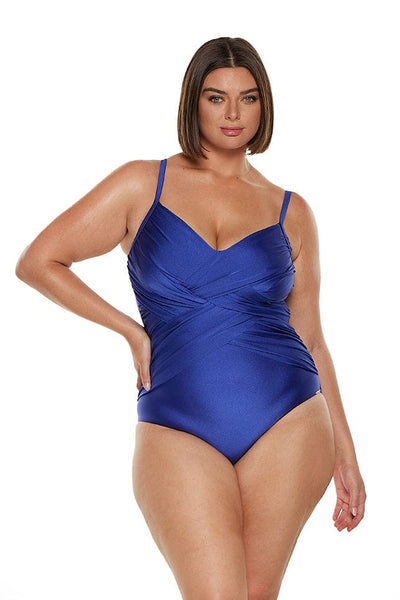 Brunette model wears royal blue v neck one piece with criss cross detail on the front