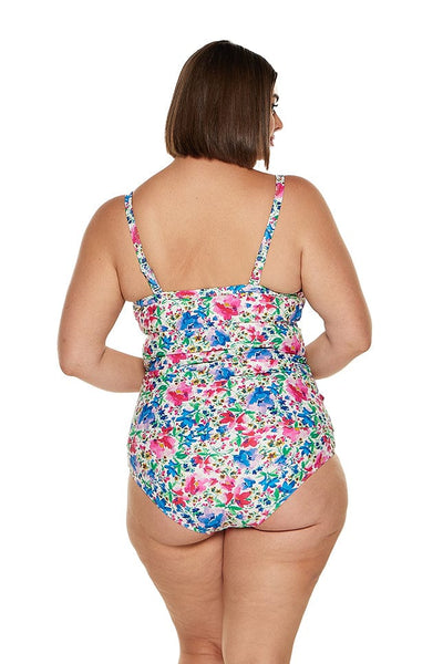 Brunette curvy model inside a studio wearing a ruched tankini top with adjustable straps in bright floral coloured print