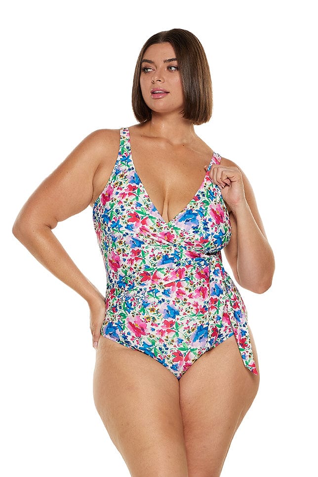 Brunette curve model wearing a floral wrap one piece in bright colours