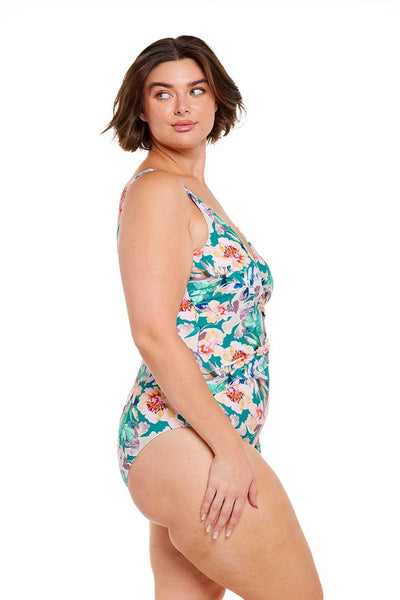 Brunette model wears teal floral crossover one piece swimsuit