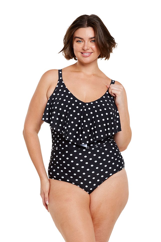 Brunette model wears v neck one piece with long frill detail in black and white dots