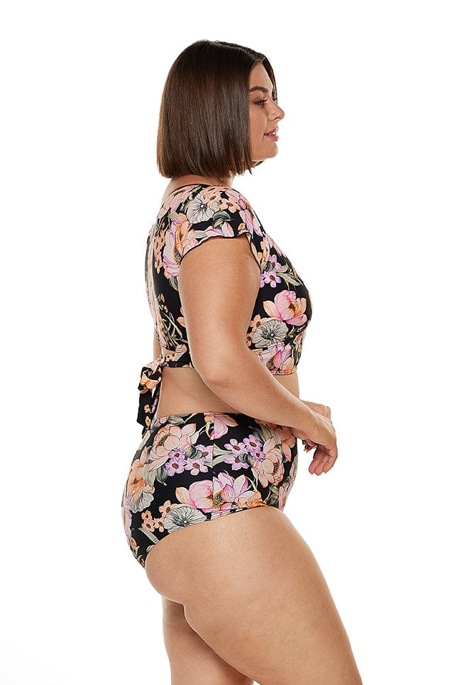 Side profile of model in studio wearing plus size high waisted floral bikini bottoms