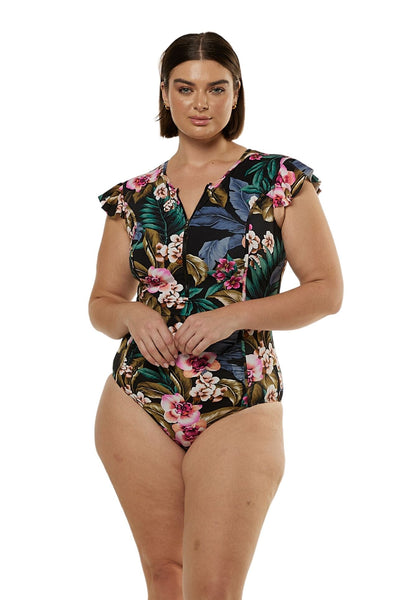 Front profile of brunette plus size model wearing frill sleeve swimsuit with zip front