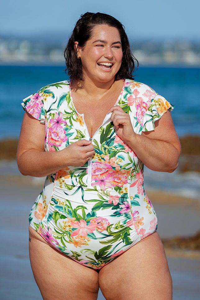 brunette plus size model wearing full coverage one piece swimsuit with frill sleeves and front zip