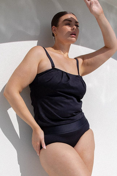 Brunette model wears flouncy black tankini
