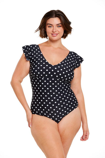 Brunette model wearing black and white dots low plunge swimsuit
