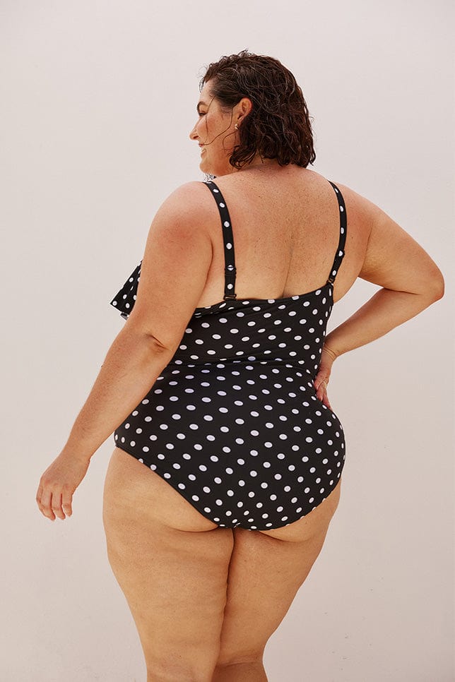 Brunette plus size model wears retro one piece in black and white dots