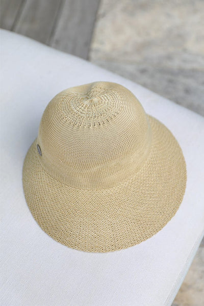 beige coloured straw hat placed on a white and natural beach chair